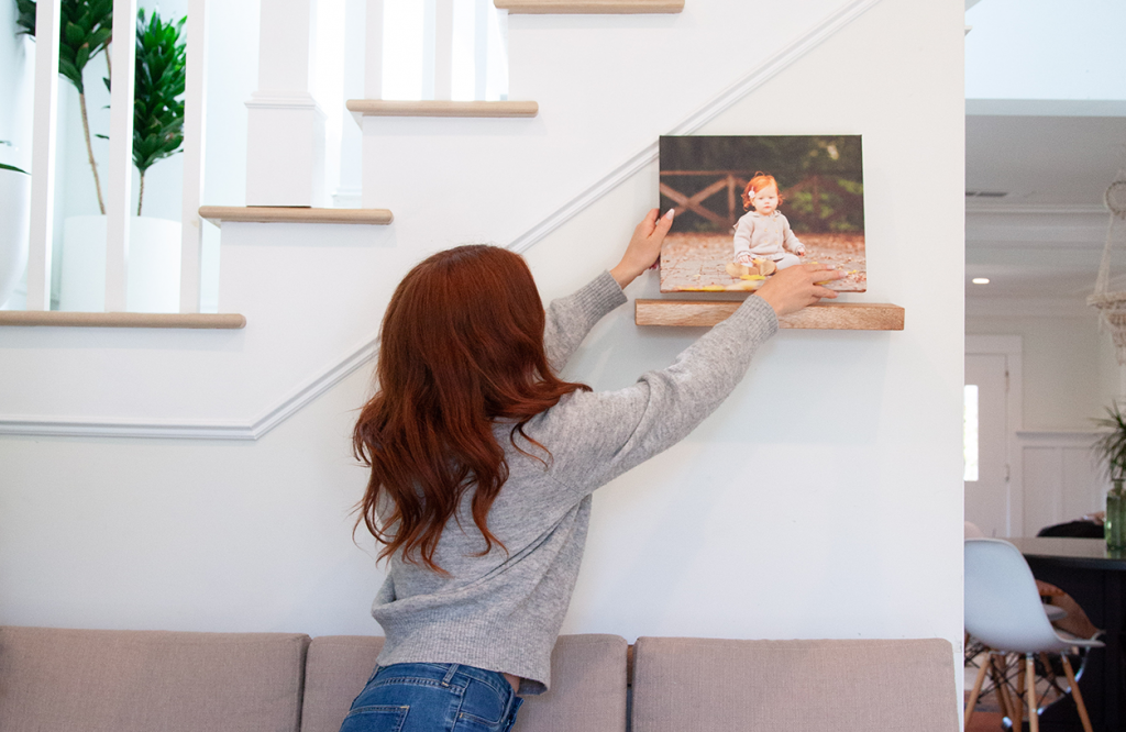 Woman places canvas print of a baby on a shelf