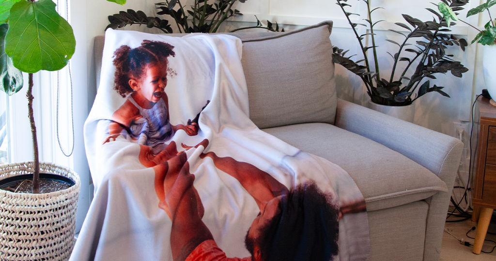 Photo blanket of a dad playing with daughter laid on a couch