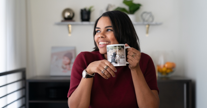 Woman holds photo mug while smiling and looking away
