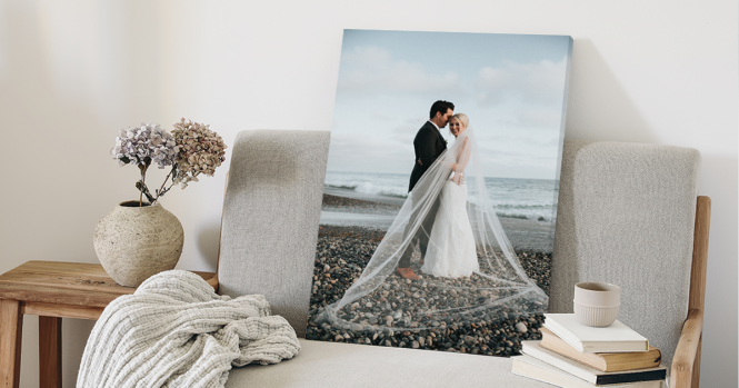 A canvas print depicting a couple on their wedding day is leaned against a chair